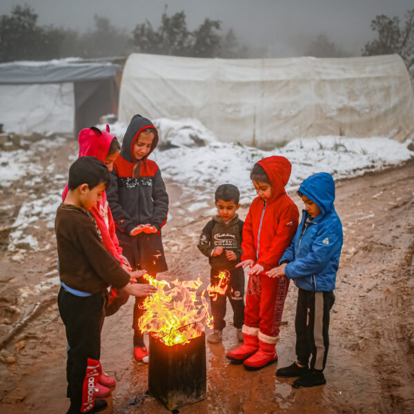 A group of children warming themselves in a primitive way 